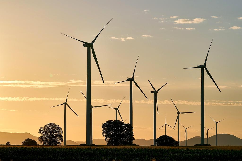 Renewable energy wind turbines in a green field with blue sky